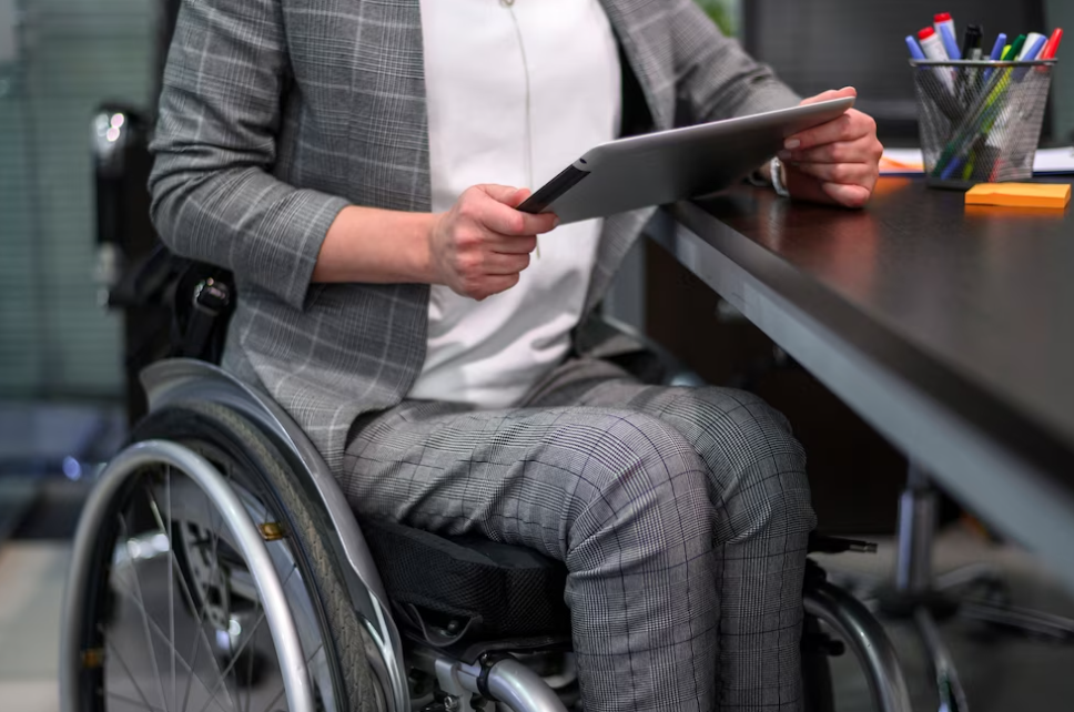 businesswoman in a gray suite in a wheelchair holds a tablet