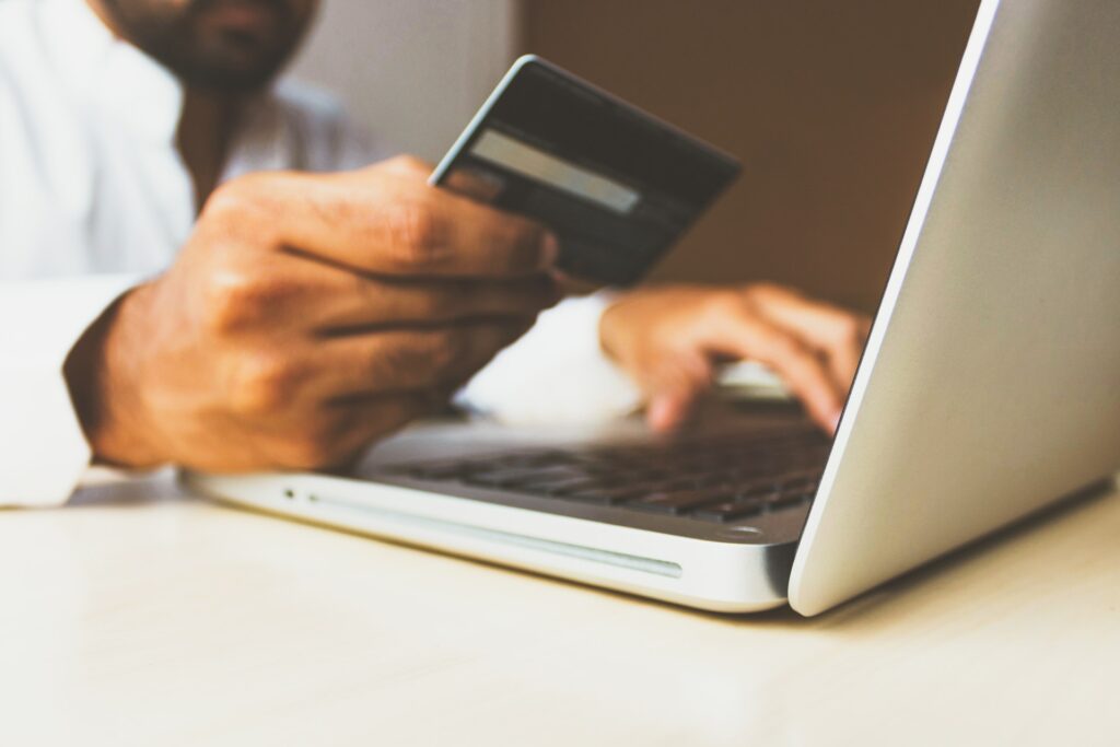 man typing on a computer and holding a credit card